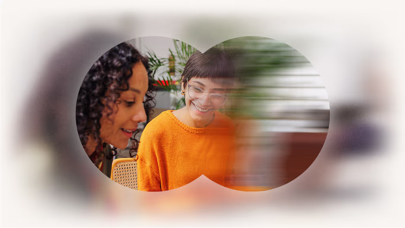 Two team members smiling and working together, seen through a stylized binocular overlay, representing Talentium's collaborative culture.